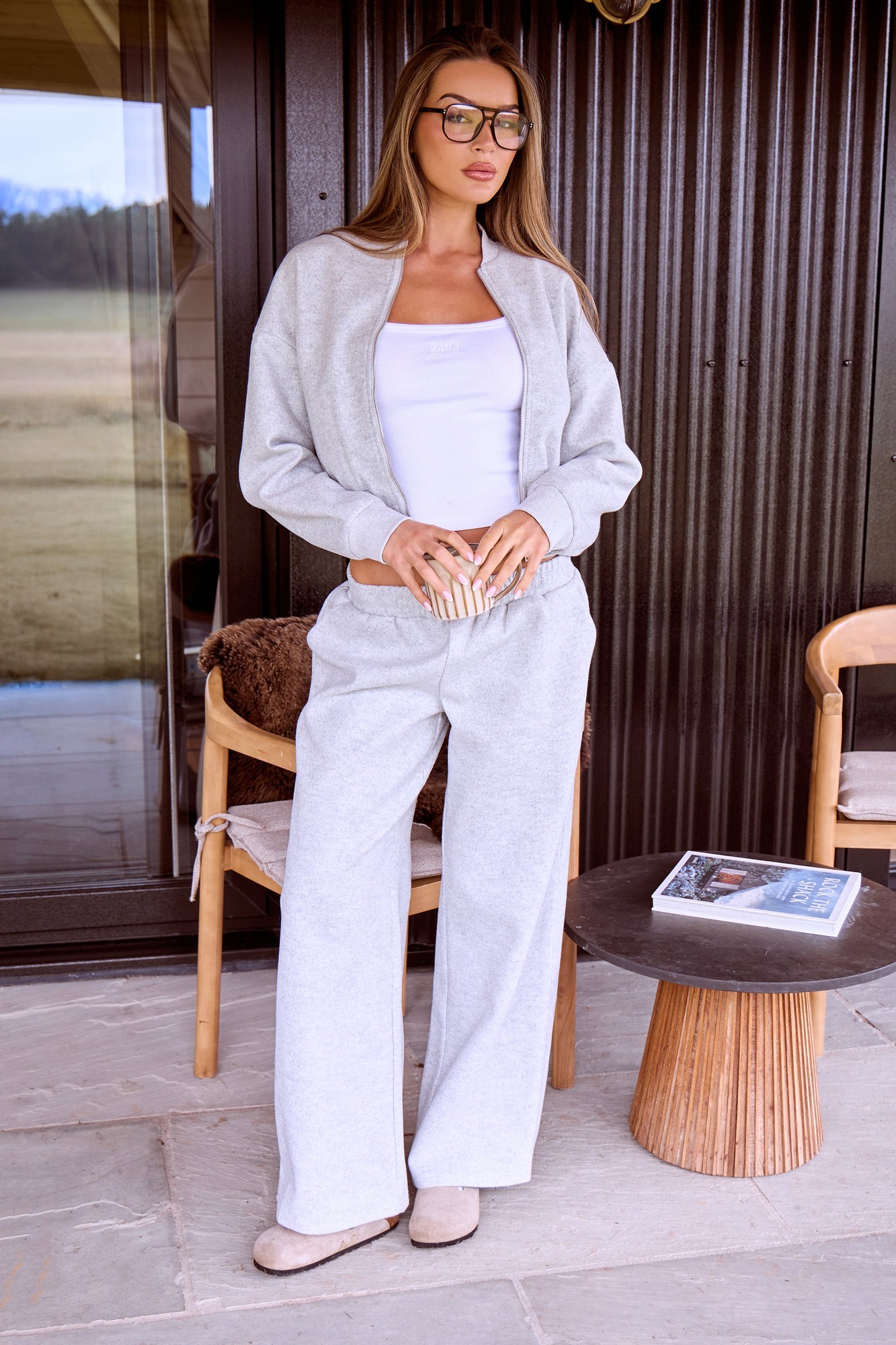 Grey marl wide leg trousers made of soft wool-effect material, featuring a relaxed fit and a drawstring waist, styled with a matching grey top and accessorized with glasses.