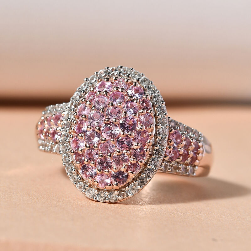 Rose gold ring featuring an oval cluster of pink gemstones surrounded by a halo of smaller white stones, set on a textured band for added elegance.