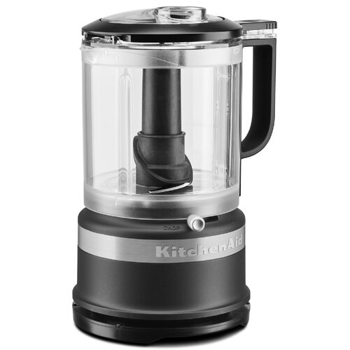 Matte black KitchenAid mini food chopper with a transparent bowl, a black feeding tube, and a silver band, featuring a simple control knob on the front.