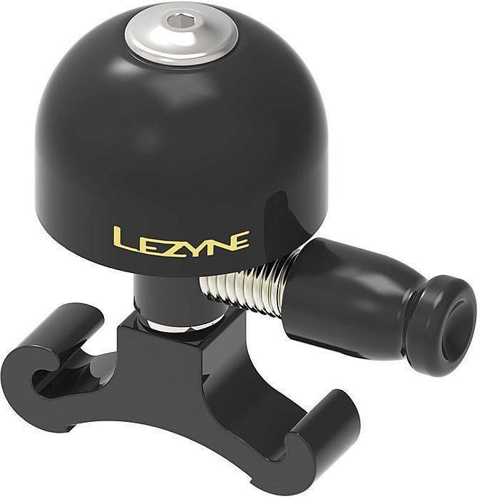 Small black brass bicycle bell with a shiny silver top, featuring a coiled spring and a sturdy mounting bracket, embossed with the Lezyne logo in gold.