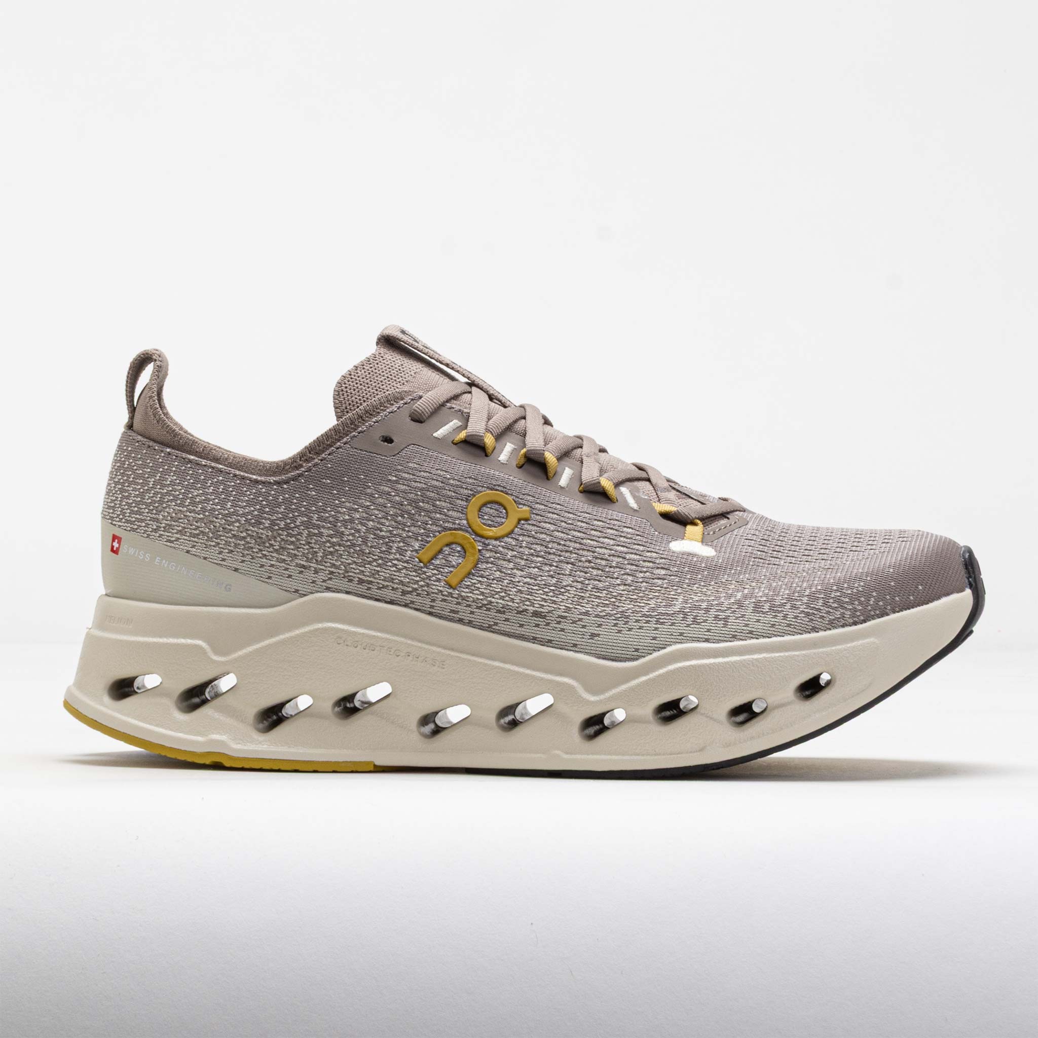 Men's On Cloudsurfer Max running shoes in Cinder and Pelican colors, featuring a synthetic upper, cushioned sole, and distinctive ventilation holes for breathability.