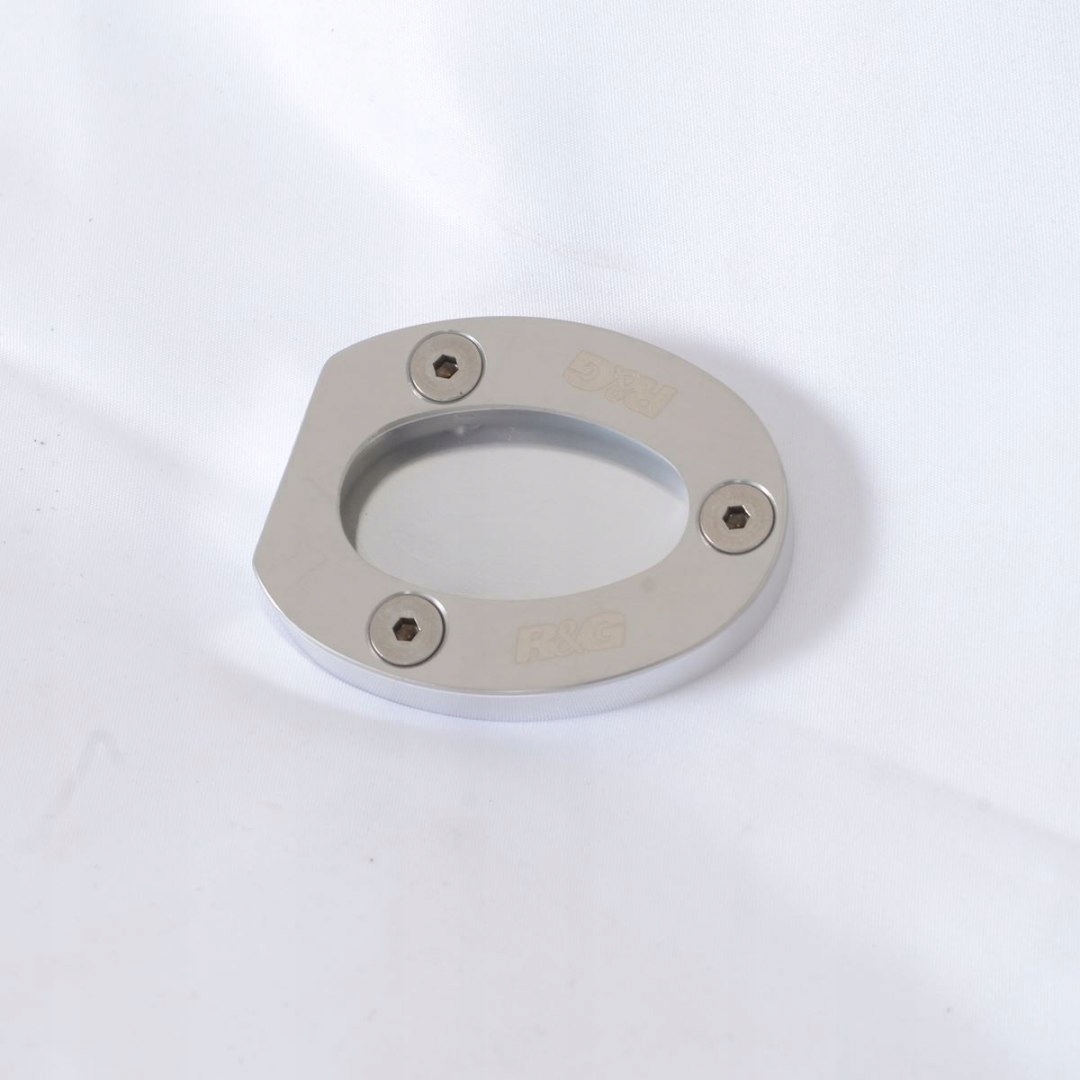 Silver aluminum kickstand shoe with a rounded oval shape, featuring a clear center and four visible screws, branded with "R&G" and "DMI" engravings.