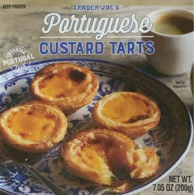 Golden-brown Portuguese custard tarts displayed on a decorative blue and white plate, with a cup of coffee in the background, highlighting their flaky crust and creamy filling.