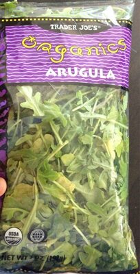 Clear plastic bag filled with fresh, vibrant green arugula leaves, labeled "Organics Arugula" with a purple and yellow design, featuring USDA organic certification.