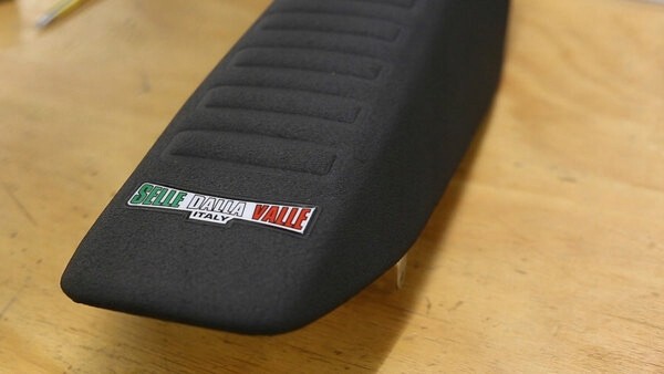 Black Selle Dalla Valle Wave seat cover with textured surface and raised stripes, designed for Honda CRF450R models from 2009 to 2012, featuring a logo in green, white, and red.