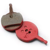 Red SRAM Avid BB5 disc brake pads, one with organic surface, circular shape with handle.