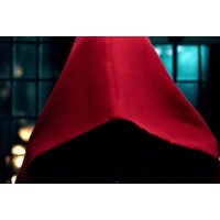 Red hooded cloak against a dark, moody background with soft lighting, suggesting a mysterious game night theme.