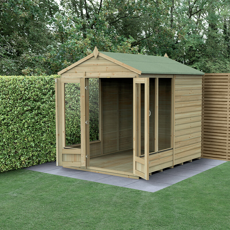 A wooden summer house with a green apex roof, featuring double doors and five windows, set on a paved area surrounded by greenery.
