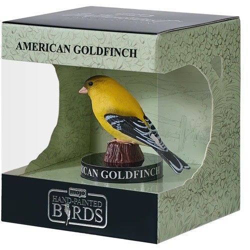 Bright yellow American Goldfinch figurine perched on a brown base, displayed in a decorative box featuring nature illustrations and the label "Hand-Painted Birds."