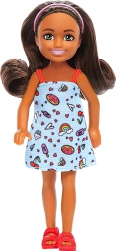 Barbie Chelsea doll features brown hair, green eyes, and wears a removable blue dress adorned with colorful patterns, complemented by red sandals and a pink headband.