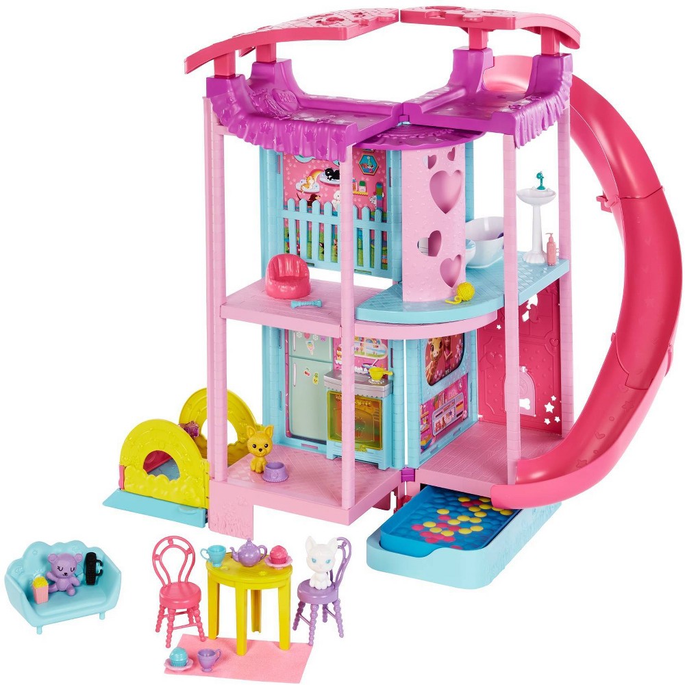 Colorful Barbie Chelsea Playhouse features pink and blue sections, a slide, furniture, and playful accessories like a teddy bear and tea set, perfect for imaginative play.