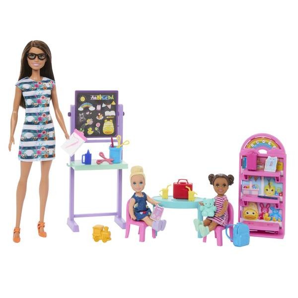 Barbie Classroom Playset features a teacher doll in a striped dress, two student dolls, a colorful chalkboard, a round table with chairs, and a vibrant storage shelf filled with school supplies.