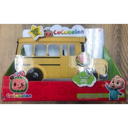 Bright yellow school bus toy with CoComelon branding, featuring a large button labeled "Try Me!" and cartoon character graphics, set against a colorful packaging backdrop.