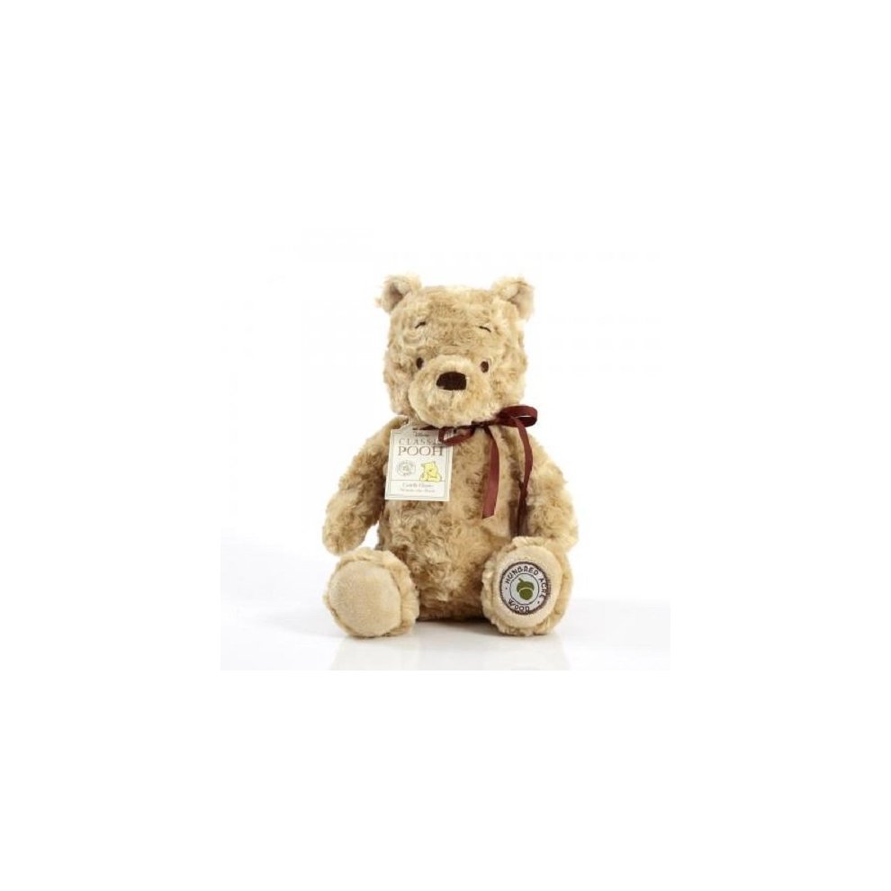 Cuddly soft toy of Winnie the Pooh, featuring a beige plush exterior, round face, stitched nose, and a brown ribbon around its neck, with a tag attached.