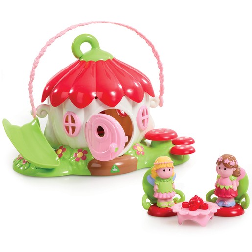 Colorful fairy flower house playset with a red flower-shaped roof, pink door, green slide, and two figurines sitting at a table with a cake.