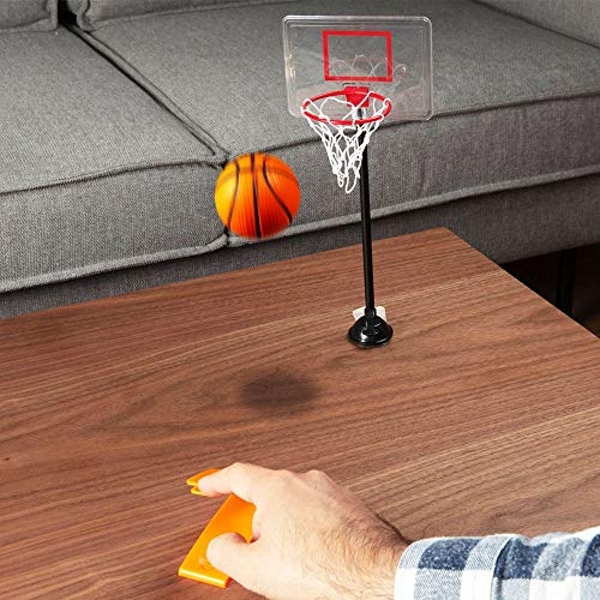 Mini table basketball game with an orange basketball, clear backboard, white net, and a black stand, played with an orange controller on a wooden tabletop near a gray couch.