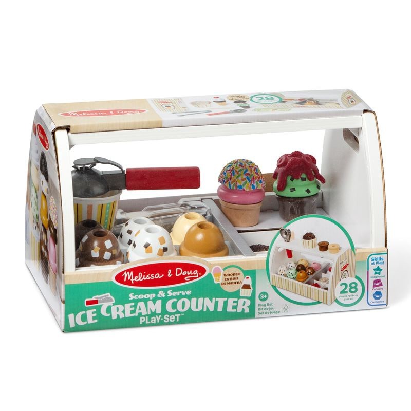Colorful wooden ice cream counter playset featuring various ice cream cones, toppings, and a scoop, packaged in a clear box with a striped design and playful graphics.