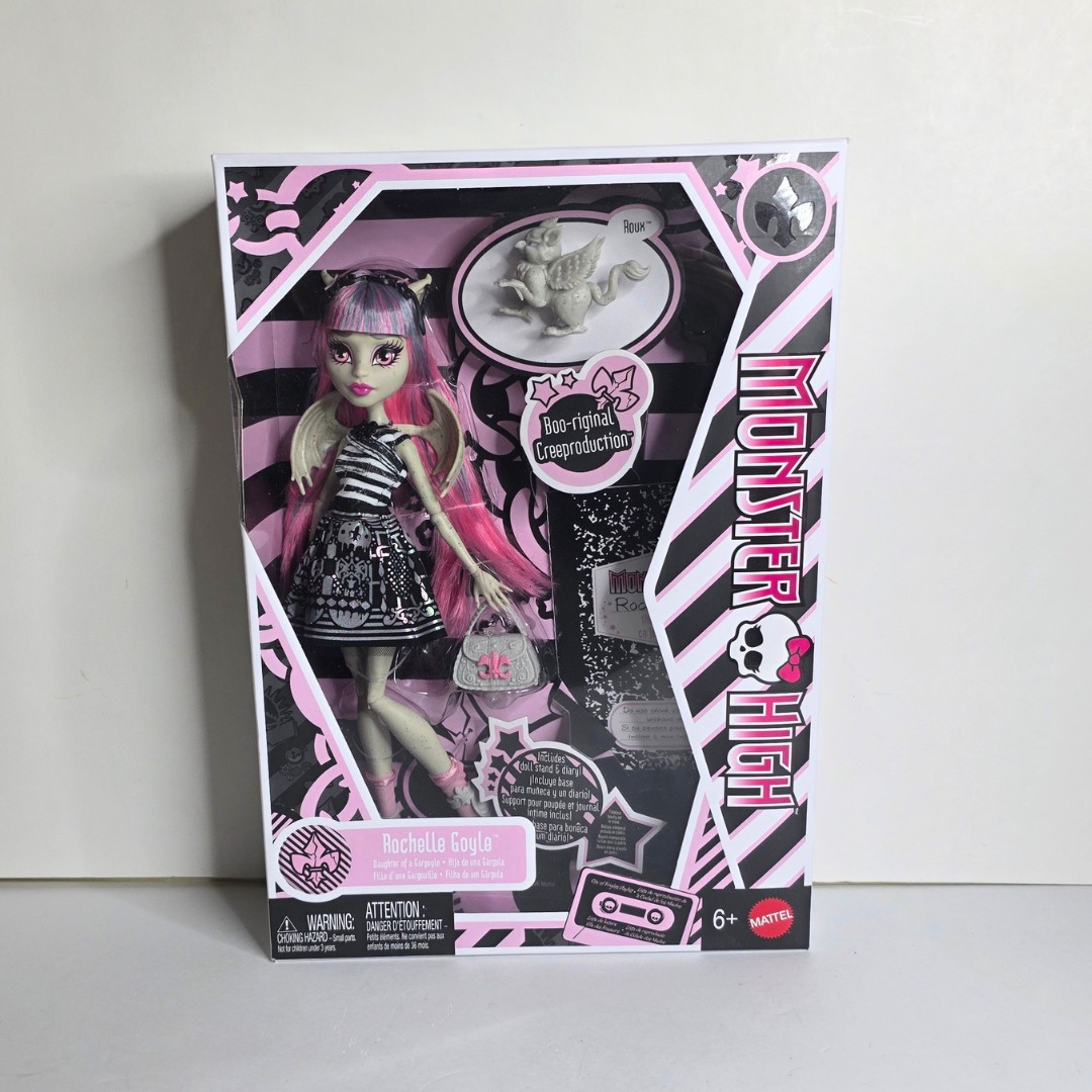 Rochelle Goyle doll in a black and pink outfit with a diary, doll stand, and a pet, all packaged in a vibrant Monster High box featuring a spooky design.