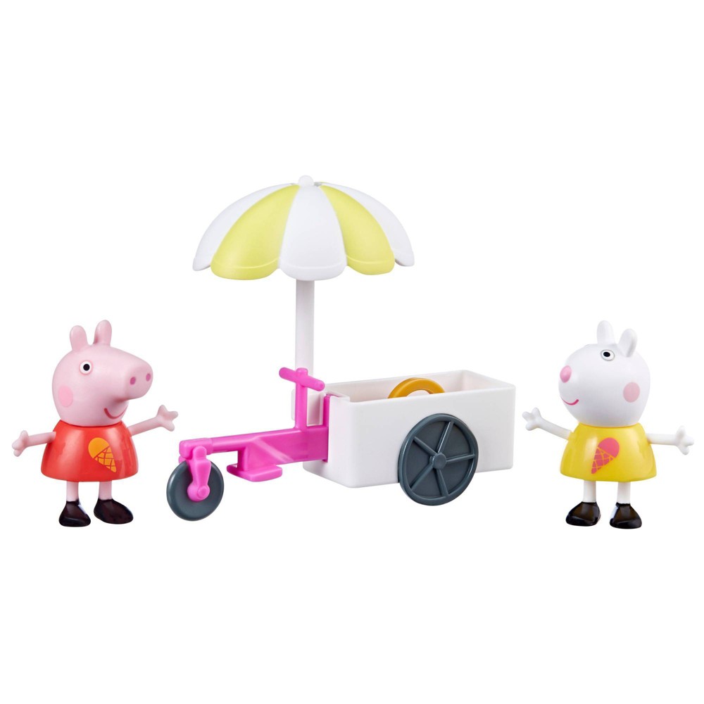 Peppa Pig and her friend Suzy Sheep stand beside a colorful ice cream cart with a yellow umbrella, featuring pink wheels and an ice cream cone design on their outfits.