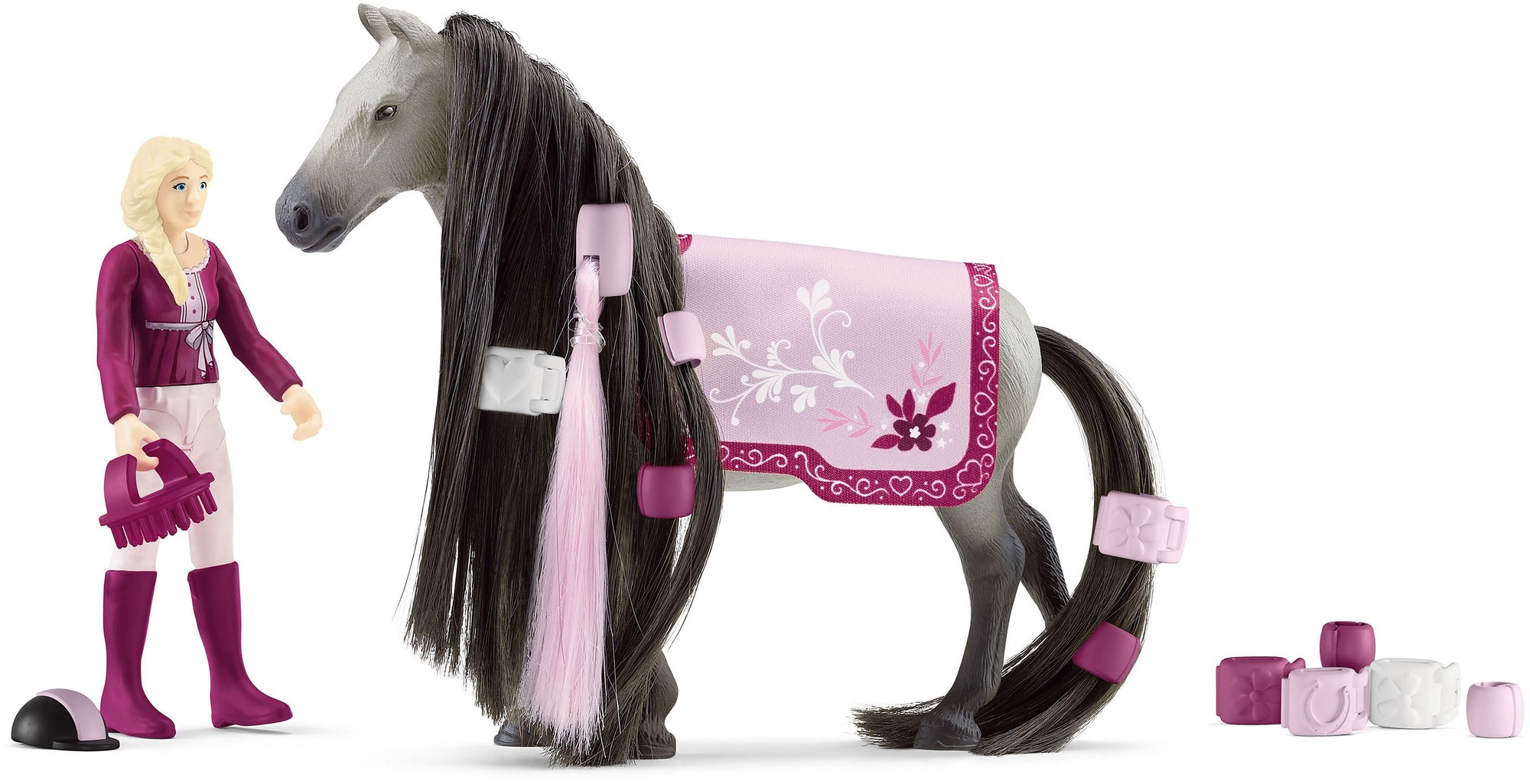 A blonde female figure in a purple outfit stands beside a grey horse with long black mane, adorned with a pink saddle featuring floral designs and colorful grooming accessories.