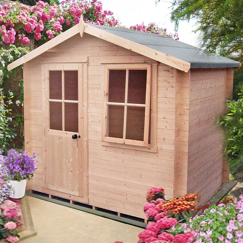 A wooden log cabin summerhouse in natural wood color, featuring a sloped roof, two front windows, and a door, surrounded by vibrant flowers and greenery.