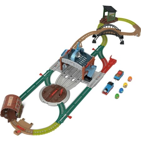Colorful train track set featuring a blue motorized train, a barrel delivery system, and various track pieces in green and gray, designed for interactive play with Thomas & Friends characters.