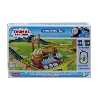 Thomas & Friends Dockside Delivery set features a blue plastic train with a smiling face, carrying a wooden cargo on a green track with hills and a colorful backdrop.