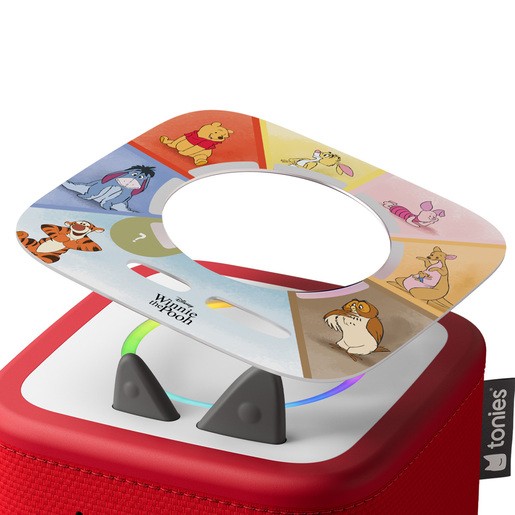 Colorful game board featuring Winnie the Pooh characters, with a circular cutout, placed on a red Toniebox, showcasing interactive play features and vibrant illustrations.