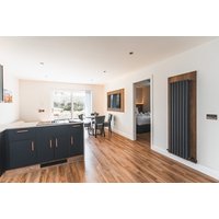 Modern cottage interior with wood flooring, dark cabinets, dining table, and large window; part of Jackton Distillery offer.