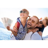 Smiling family with sunglasses and tickets, enjoying a sunny day by the water, promoting Kids Pass adventures.