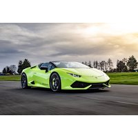 Lime green Lamborghini supercar on a racetrack with cloudy sky and trees in the background.