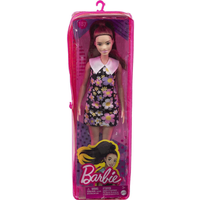 Barbie Fashionista doll with brunette ponytail, wearing a black dress with colorful flowers, in pink packaging.