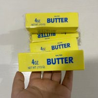 Yellow butter stick fidget toy with blue text, 4oz label, resembling real butter, held in a hand.