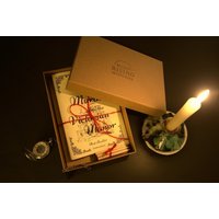 Virtual Murder Mystery Dinner Party Game box with candle, magnifying glass, and themed booklet.