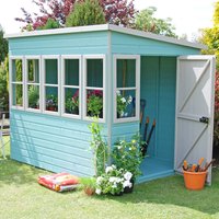 Teal wooden garden potting shed with five windows, open door, and a slanted roof, surrounded by plants and tools.