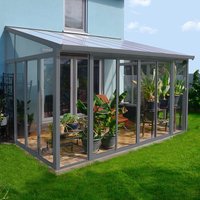 Grey lean-to conservatory with clear panels, slanted roof, and metal frame, attached to a house, featuring potted plants.