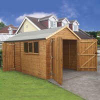 Wooden garage shed with shiplap cladding, double doors, side window, pitched roof, set on grass with house in background.
