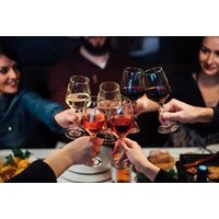 Group toasting with assorted wine glasses over a dining table with plates and food at Alba Bar & Grill.