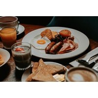 Breakfast plate with eggs, sausages, bacon, hash browns, toast, and drinks at Clayton Hotel Birmingham City Centre.