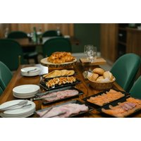 Table with assorted breakfast items, including pastries, smoked salmon, and meats, set in a cozy dining room.