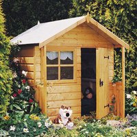 Wooden playhouse with pitched roof, front window, and open door, surrounded by greenery and flowers.