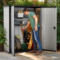 Tall Keter Hi-Store Plus shed, gray with double doors, black trim, and internal shelves, storing garden tools and supplies.