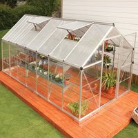 Silver Palram Canopia greenhouse with polycarbonate panels, pitched roof, and sliding door on wooden platform.