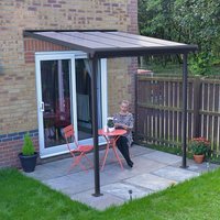 Grey patio cover with clear panels, supported by dark frame, attached to brick wall, covering small outdoor seating area.