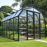 Clear 8x12 Palram Canopia Rion greenhouse with dark frame, pitched roof, and wide double doors in a garden setting.