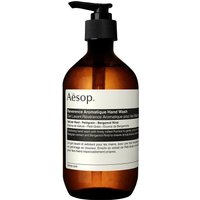 Amber bottle with black pump dispenser labeled "Aesop Reverence Aromatique Hand Wash 500 ml" in minimalist design.
