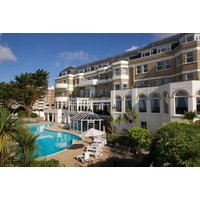 Bournemouth Carlton Hotel with outdoor pool, sun loungers, and palm trees, featuring classic architecture and large windows.