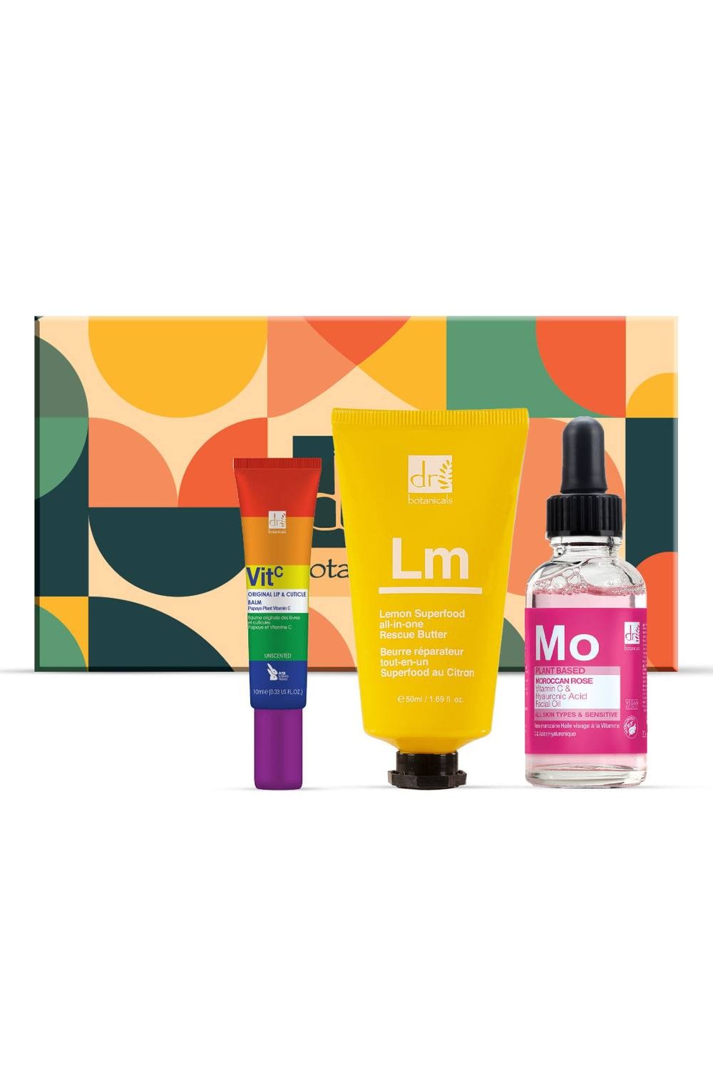 Vegan skincare gift set featuring three products: a purple and orange tube, a yellow and green jar, and a pink dropper bottle, all presented in a colorful geometric box.