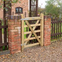 Wooden Croft Prestige gate with diagonal cross-brace, framed by brick posts, set in a rustic garden fence.