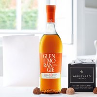 Glenmorangie Original whisky bottle, 12 chocolate truffles in black box, white occasion card on table.